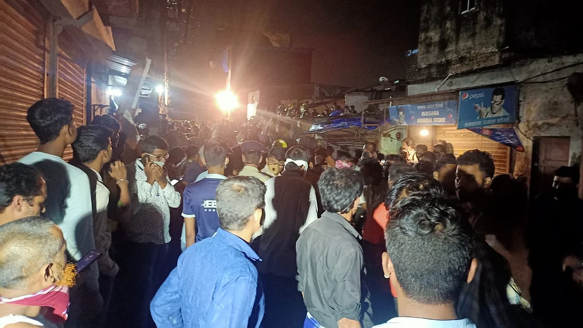 Crowd gathers around as civil authority and rescue personnel search for survivors in the debris of a building that collapsed following heavy monsoon rains, in Mumbai on June 10, 2021.