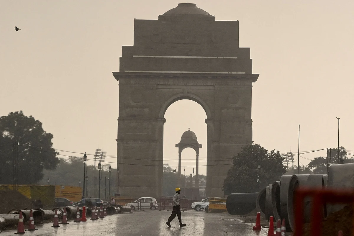 A construction worker walk near India Gate during a monsoon rainfall in New Delhi on June 17, 2021.