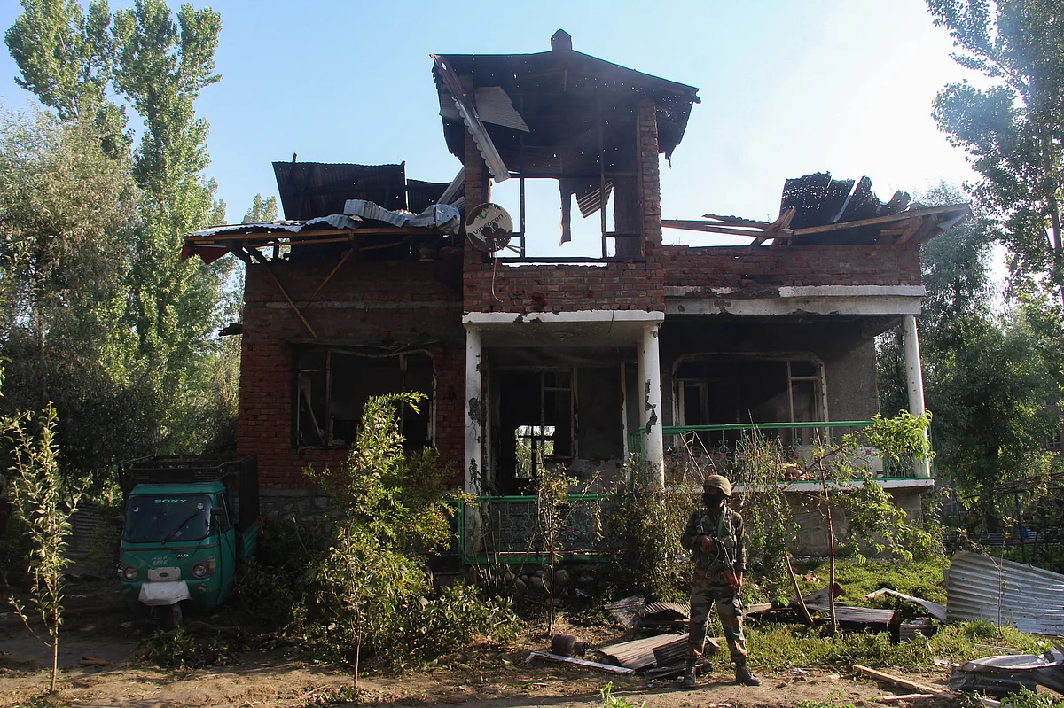 A soldier stands outside the damaged house where a gun-battle took place between suspected militants and government forces in the Maloora locality on the outskirts of Srinagar in Jammu & Kashmir.