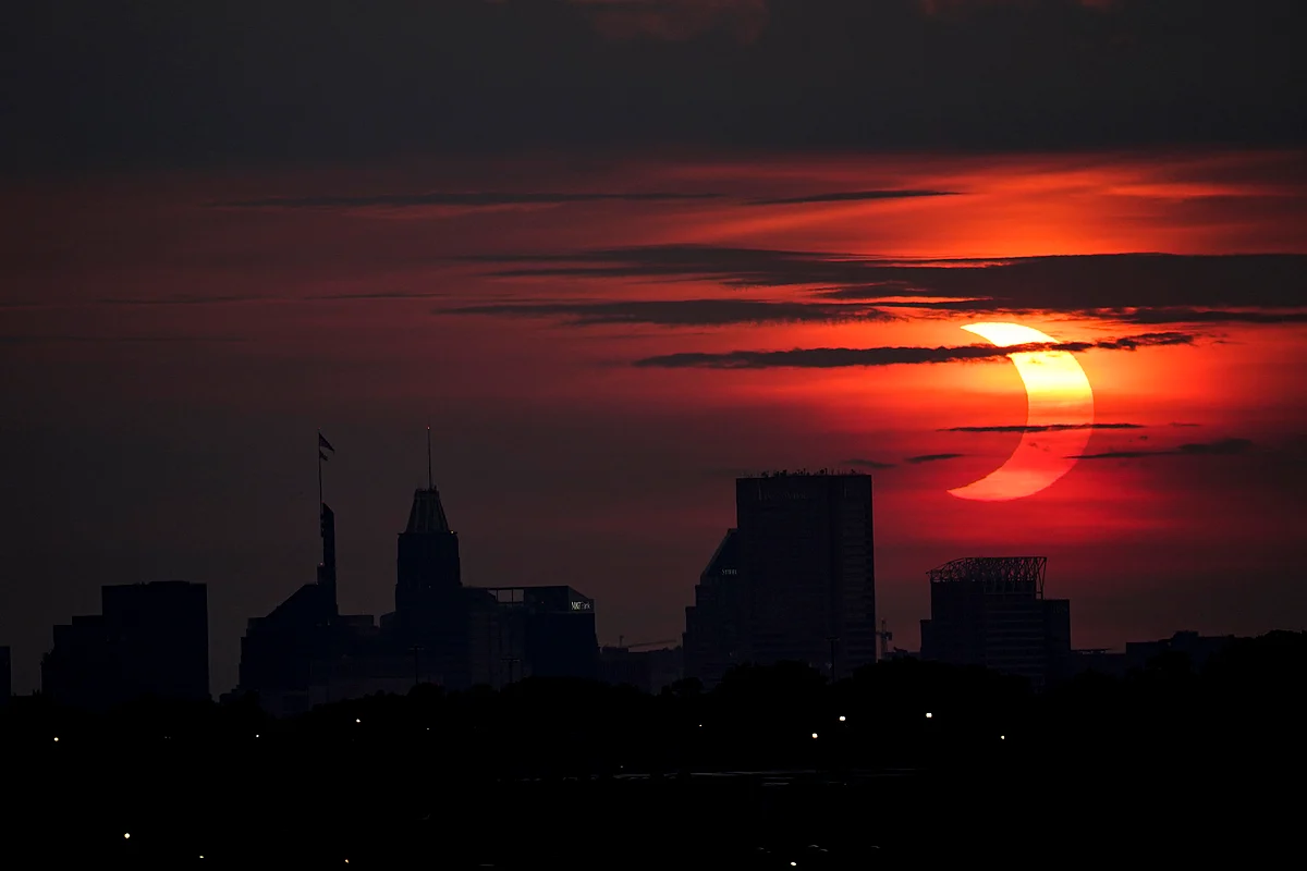 A partial solar eclipse rises over the Baltimore skyline, Thursday, June 10, 2021, seen from Arbutus, Md in the USA.