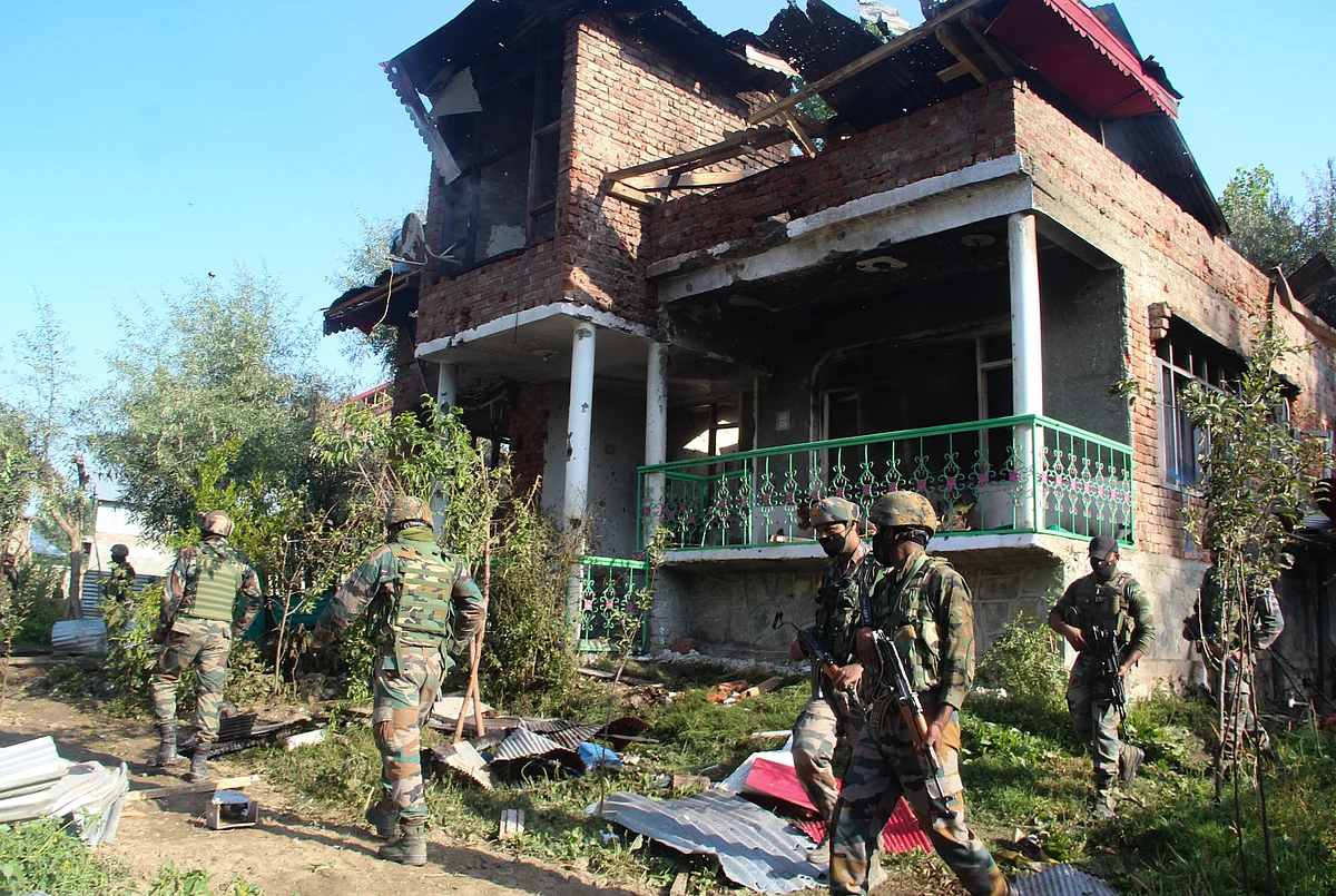 Army soldiers stand guard outside the house that was damaged during a gunfight between security forces and militants in Maloora locality on the outskirts of Srinagar, Jammu & Kashmir.