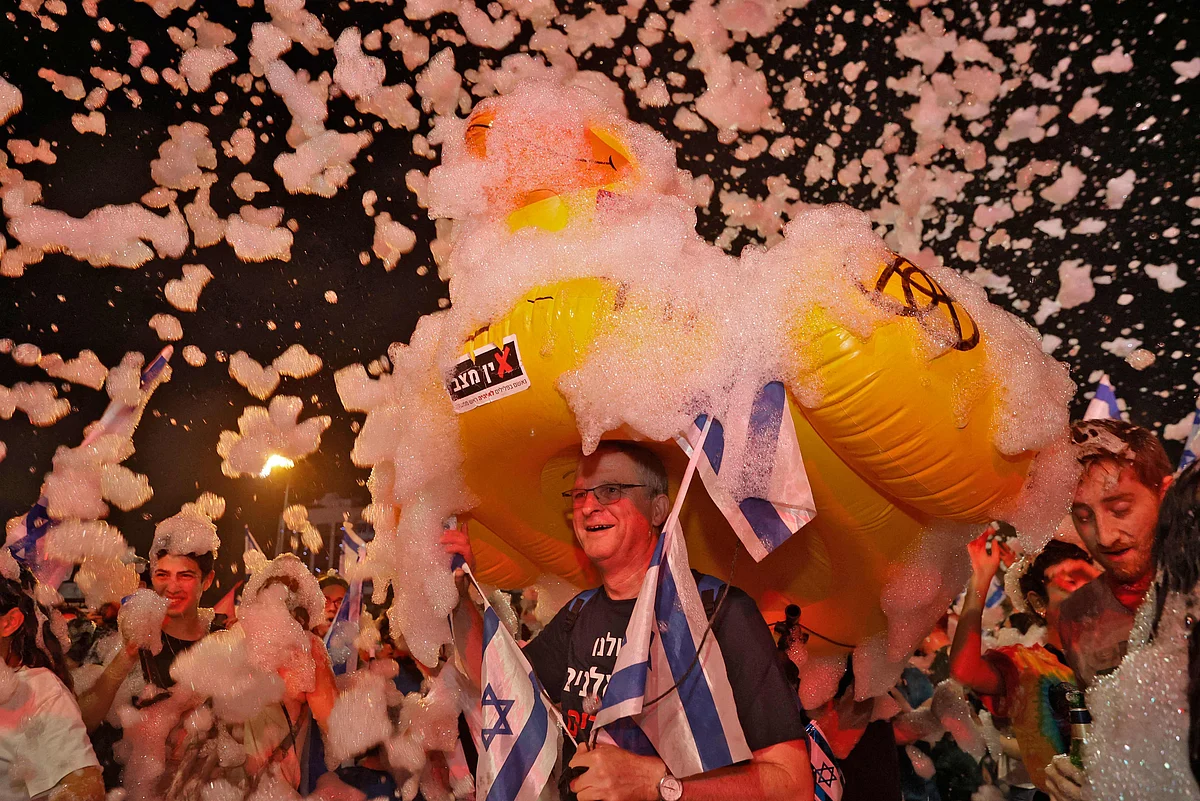 Israeli demonstrators celebrate with foam the passing of a Knesset vote confirming a new coalition government during a rally in the Mediterranean coastal city of Tel Aviv on June 13, 2021.