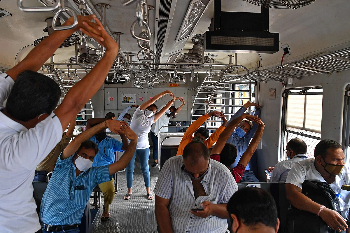 Commuters take part in a yoga session inside a train coach in Mumbai on June 21, 2021, to mark International Yoga Day.