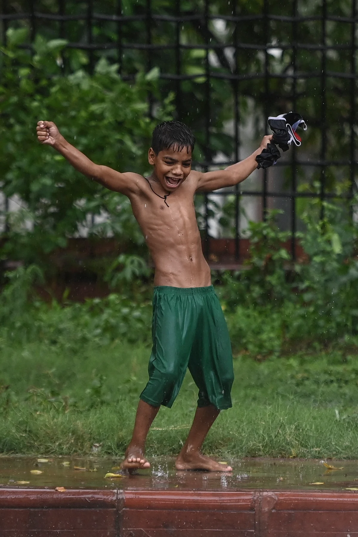 A boy plays along a footpath during a monsoon rainfall in New Delhi on June 17, 2021.