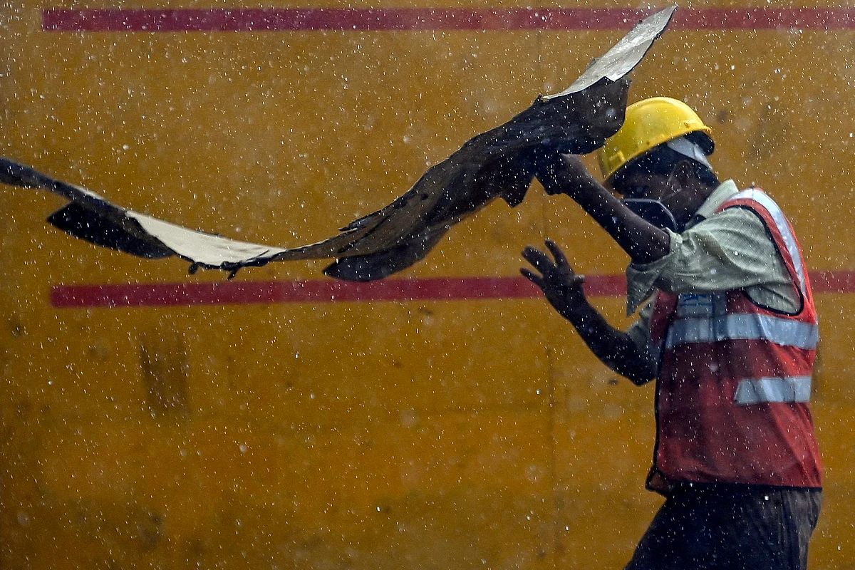 A construction worker holds a cardboard sheet to shelter during a monsoon rainfall, near India Gate in New Delhi on June 17, 2021.