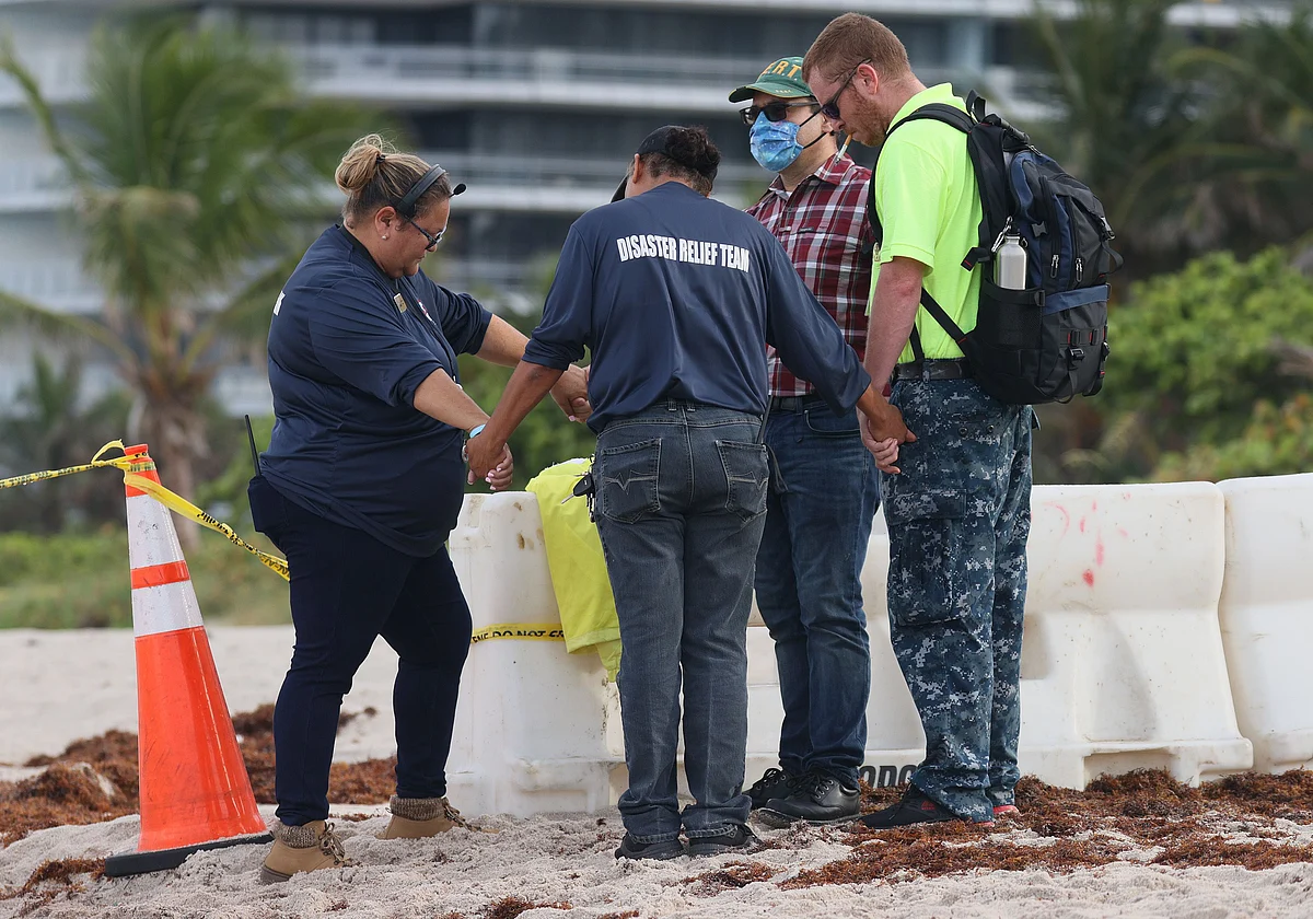 People pray together near the partially collapsed 12-story Champlain Towers South condo building on June 26, 2021 in Surfside, Florida.