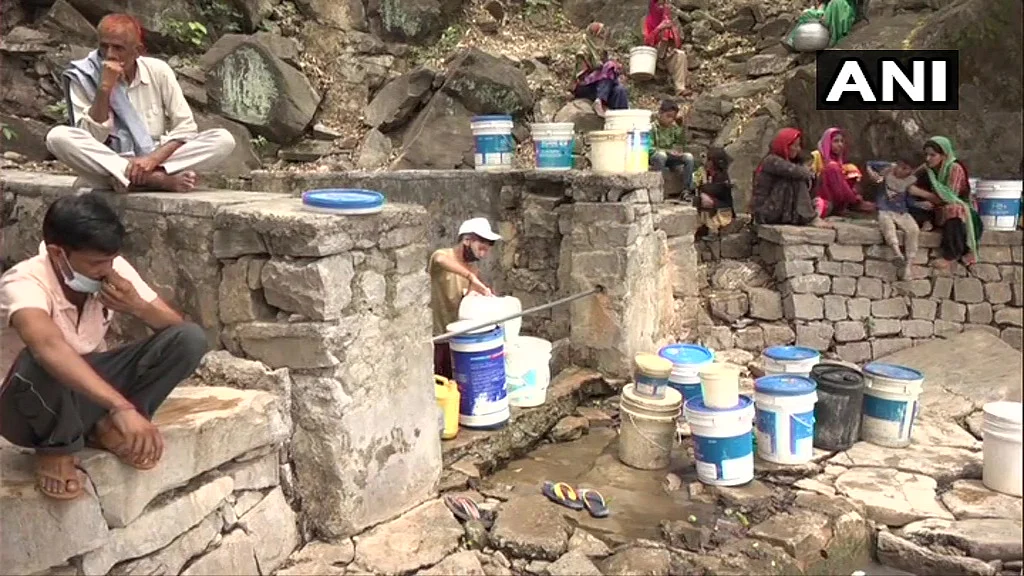 Locals gather at the pond to fill water