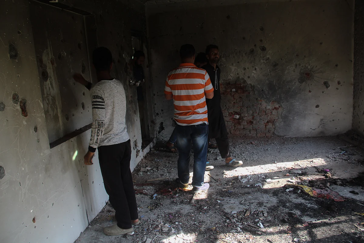 Kashmiri villagers assess the house that was damaged during a gunfight between security forces and militants in Maloora locality on the outskirts of Srinagar, Jammu & Kashmir.