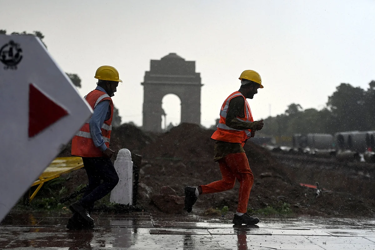 Construction workers run towards a shelter during a monsoon rainfall near India Gate in New Delhi on June 17, 2021.