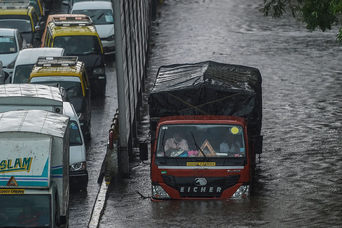 Commuters make their way through flooded roads following heavy monsoon rains in Mumbai on June 9, 2021.