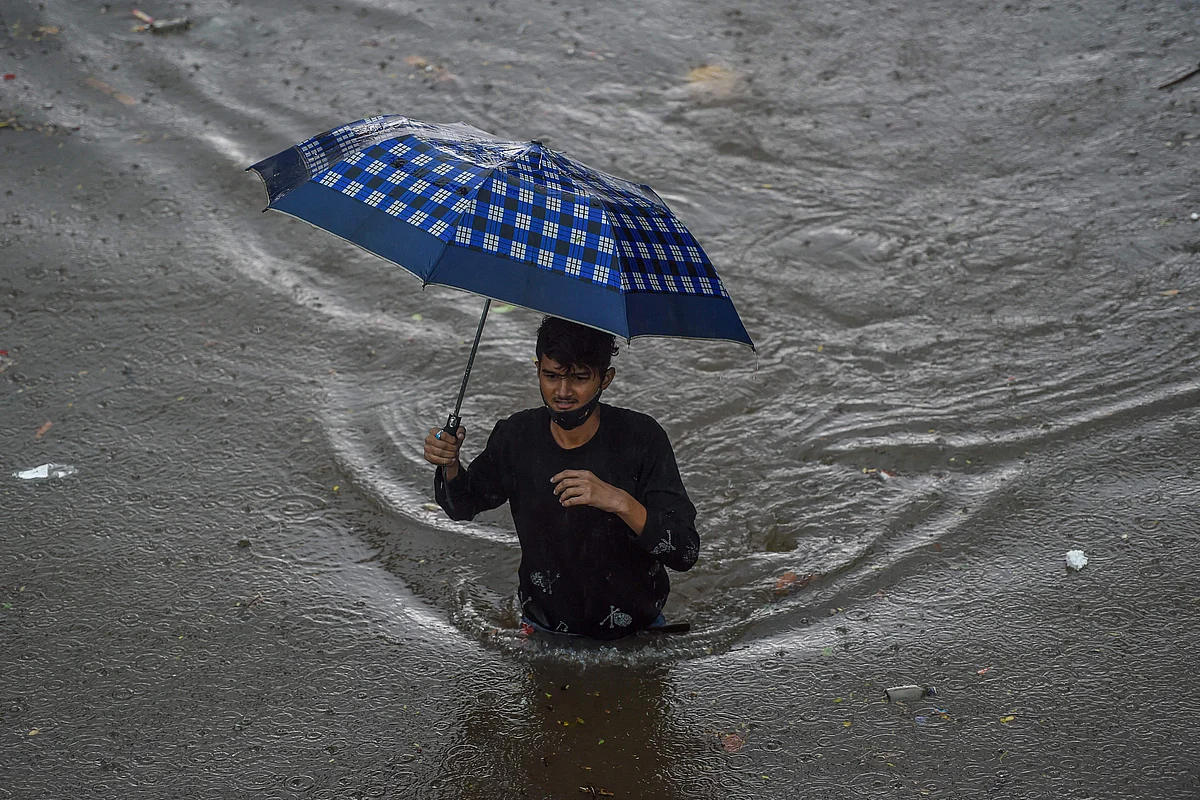A man walks on a flooded road during heavy monsoon rains in Mumbai on June 9, 2021.