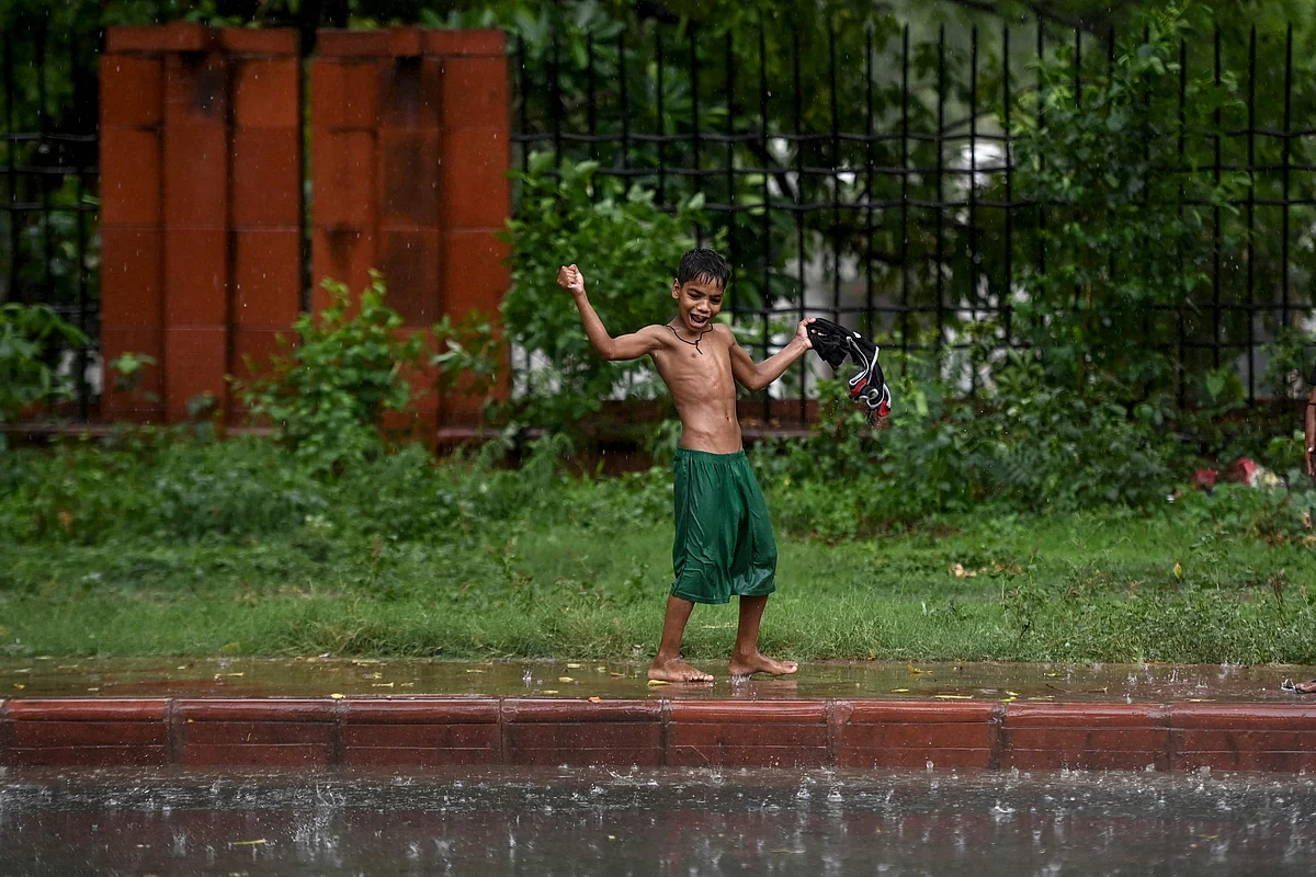A boy plays along a footpath during a monsoon rainfall in New Delhi on June 17, 2021.