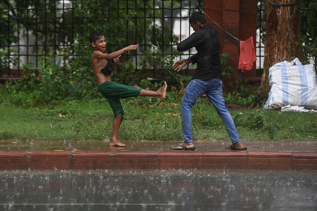 Children play along a footpath during a monsoon rainfall in New Delhi on June 17, 2021.