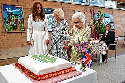 UK’s Queen Elizabeth II cuts a cake as Camilla, the Duchess of Cornwall and Kate, the Duchess of Cambridge look on at an event in celebration of ‘The Big Lunch’ initiative.