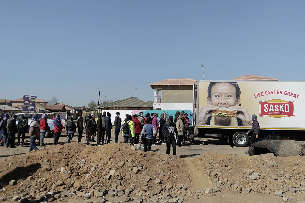 People queue to buy bread from trucks who provide food as shops and mall are looted and closed for business in Soweto, on July 14, 2020.
