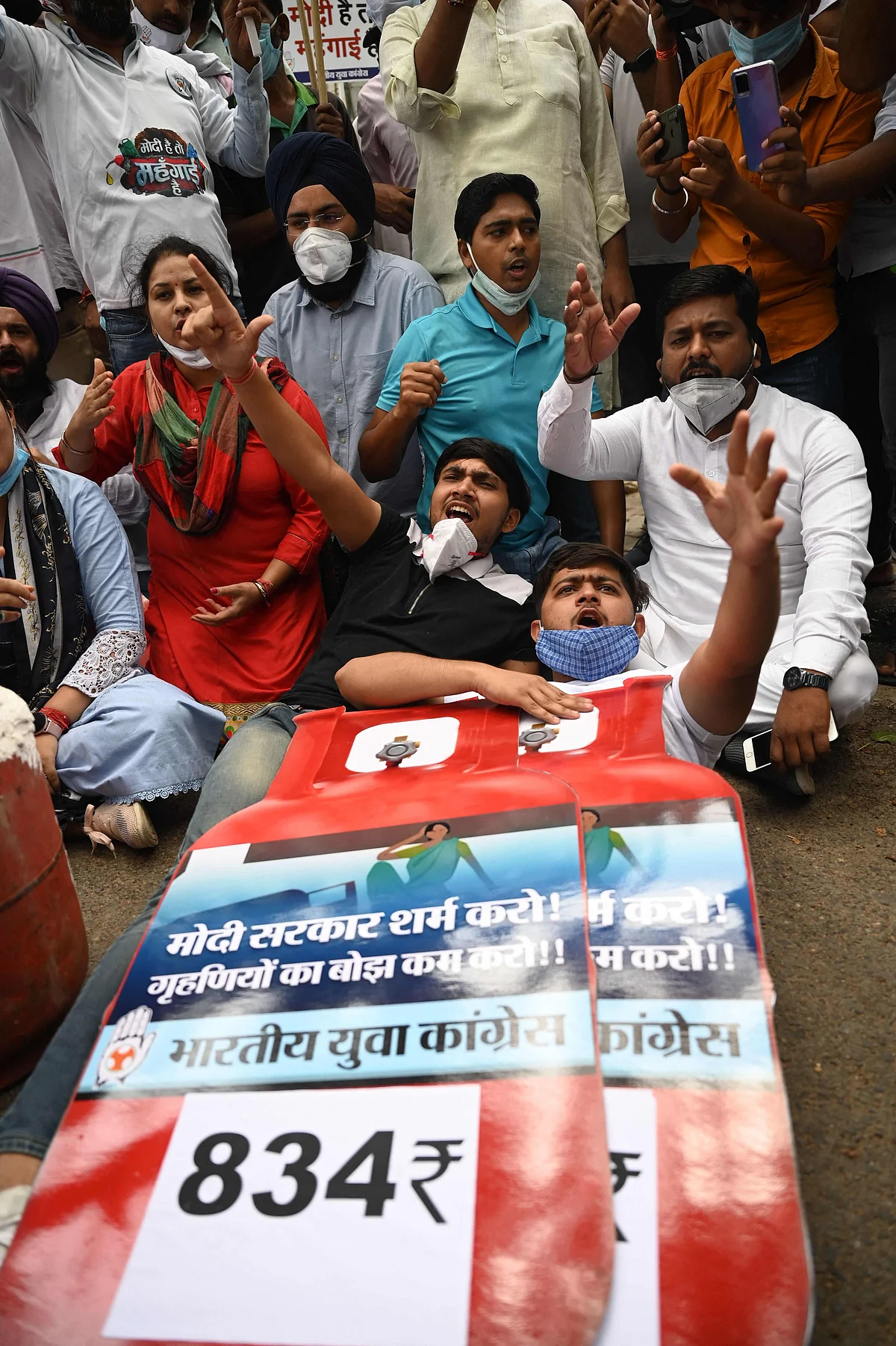 Activists of the Indian Youth Congress (IYC) party hold a large Liquefied Petroleum Gas (LPG) cylinder cutout while shouting slogans during a protest against the recent price hike of fuel and LPG, outside the ministry of petroleum and natural gas in New Delhi on July 3, 2021.