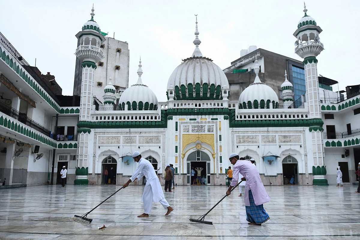 Muslim devotees remove water after a rainfall before others arrive to offer morning prayers on the occasion of the Eid al-Adha or the Festival of Sacrifice, at Jama Masjid Khairuddin in Amritsar on July 21, 2021.