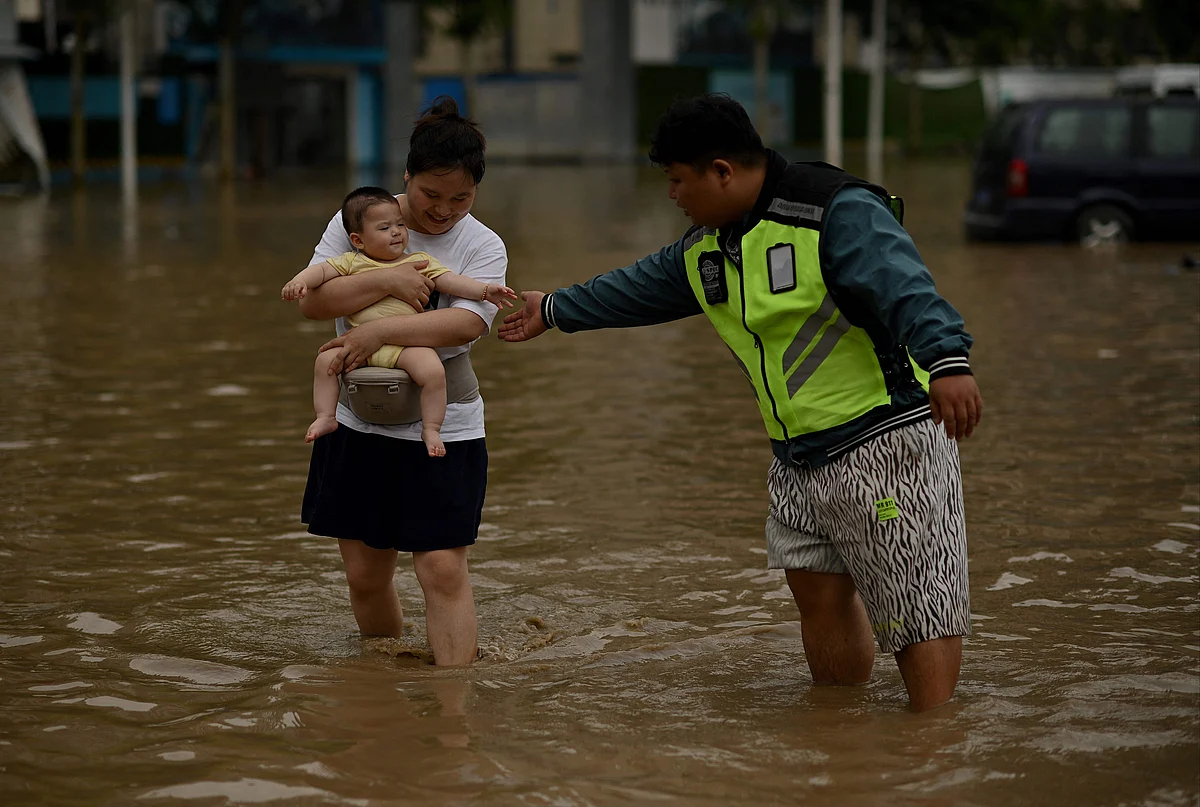 People wade through a flooded street following a heavy rain in Zhengzhou, in Chinas Henan province on July 22, 2021.