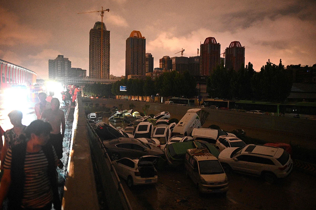 People look at cars stacked on each other at an entrance of a tunnel following a heavy rain in Zhengzhou in Chinas Henan province on July 21, 2021.