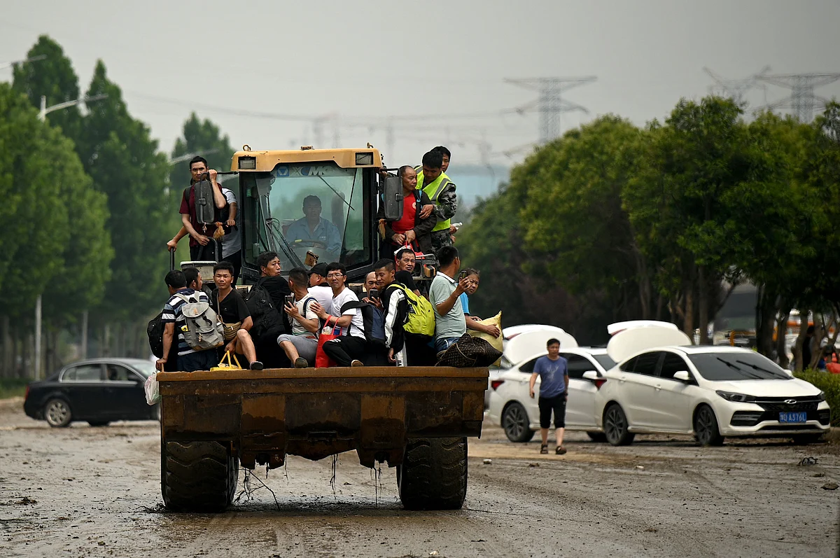 People ride on a bulldozer following a heavy rain in Zhengzhou, in Chinas Henan province on July 22, 2021.