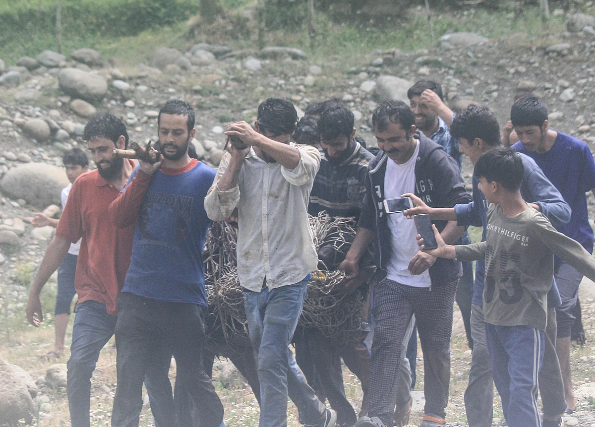 Locals and Wildlife officials carry the tranquilised black bear after it strayed along with its two cubs into northern Kashmir's Baramulla District on July 13, 2021.