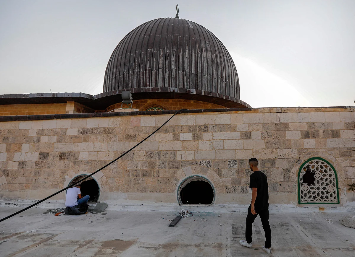 Palestinian youths look into the Al-Aqsa mosque on the first day of the Eid al-Adha feast celebrated by Muslims worldwide, on July 20, 2021, through windows which were shattered two days earlier in renewed clashes between Palestinians and Israeli police at the Al-Aqsa complex in Jerusalems old city.