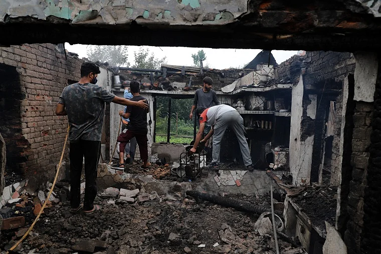 Kashmiri villagers inspect a house damaged in a gunfight in Pulwama, south of Srinagar