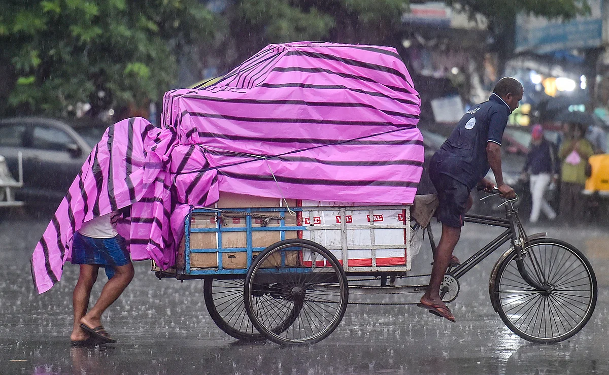 Porters carry goods on a street amid rains in Kolkata, Thursday, July 1, 2021.