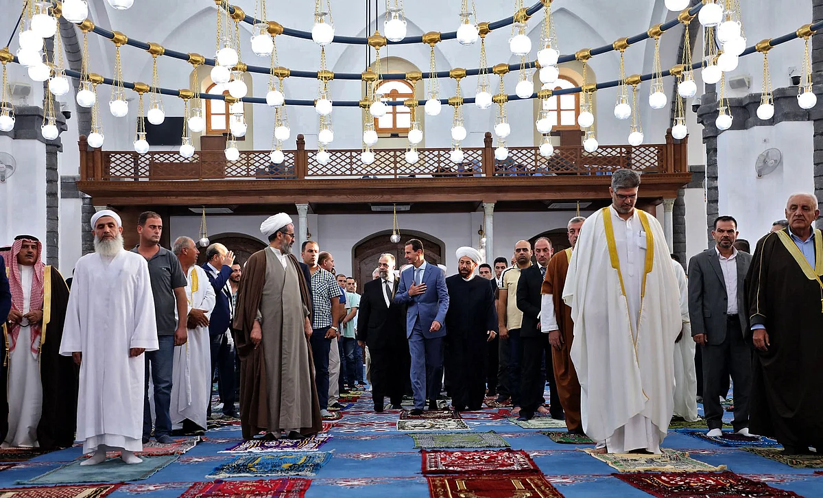 A handout picture released by the official Facebook page of the Syrian Presidency shows President Bashar al-Assad (C) performing Eid al-Adha prayer at Khaled bin al-Walid mosque in Homs on July 20, 2021.
