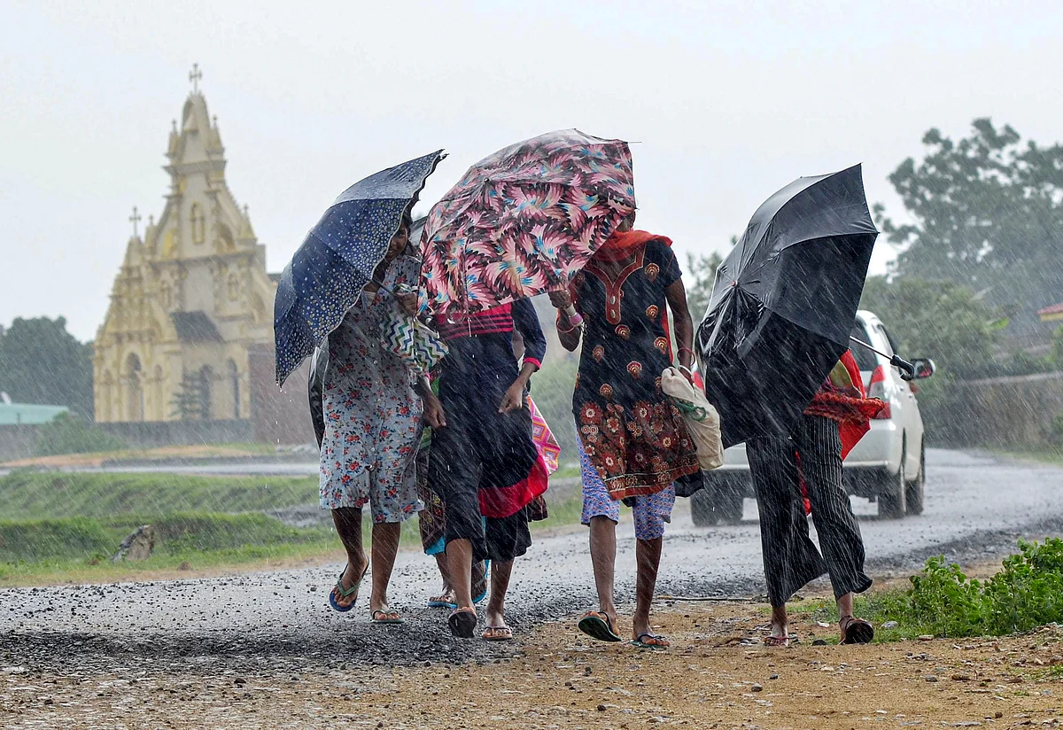 Pedestrians carrying umbrellas, cross a street amid rain in Ranchi, Friday, July 2, 2021.