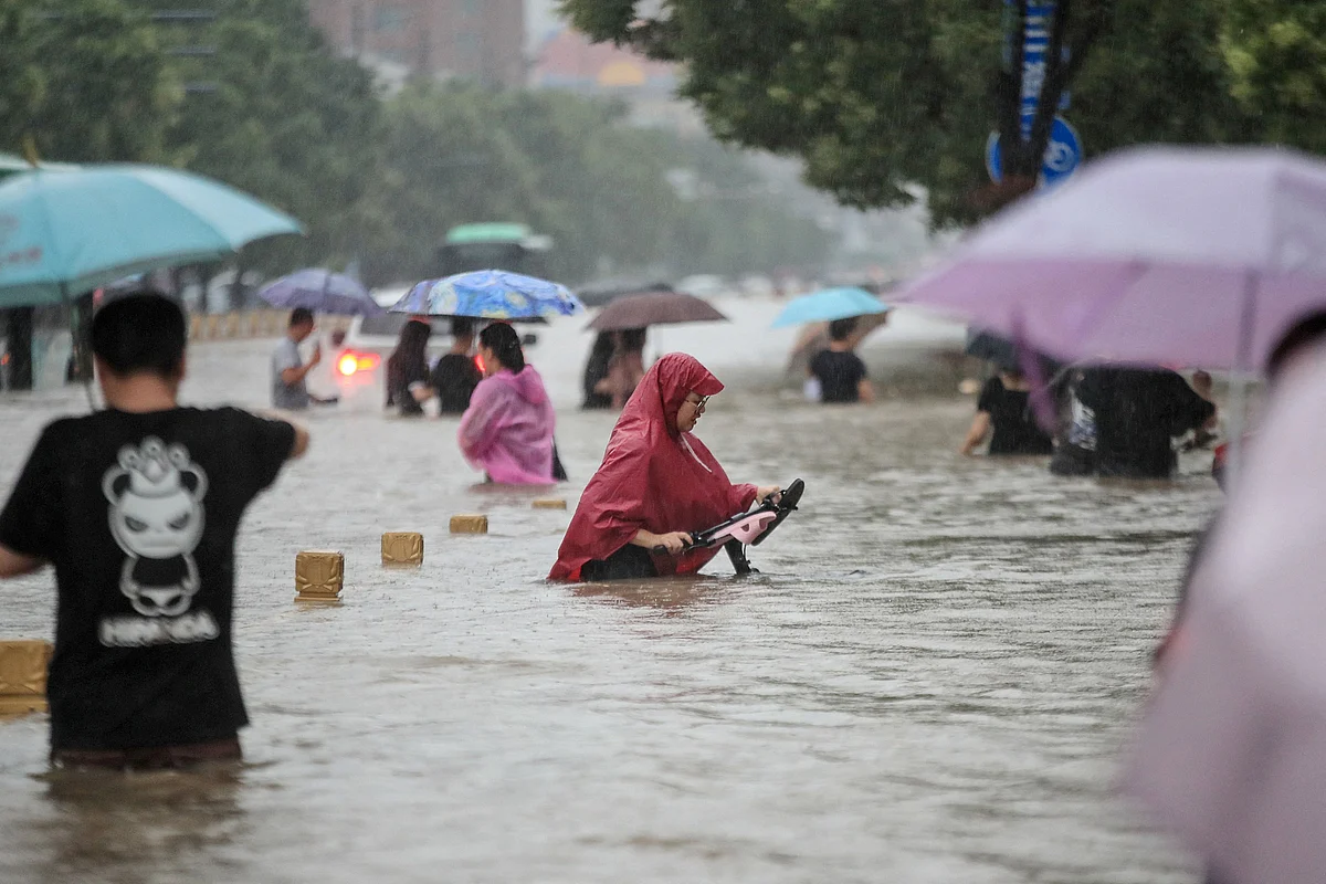 This photo taken on July 20, 2021 shows people wading through flood waters along a street following heavy rains in Zhengzhou in Chinas central Henan province.