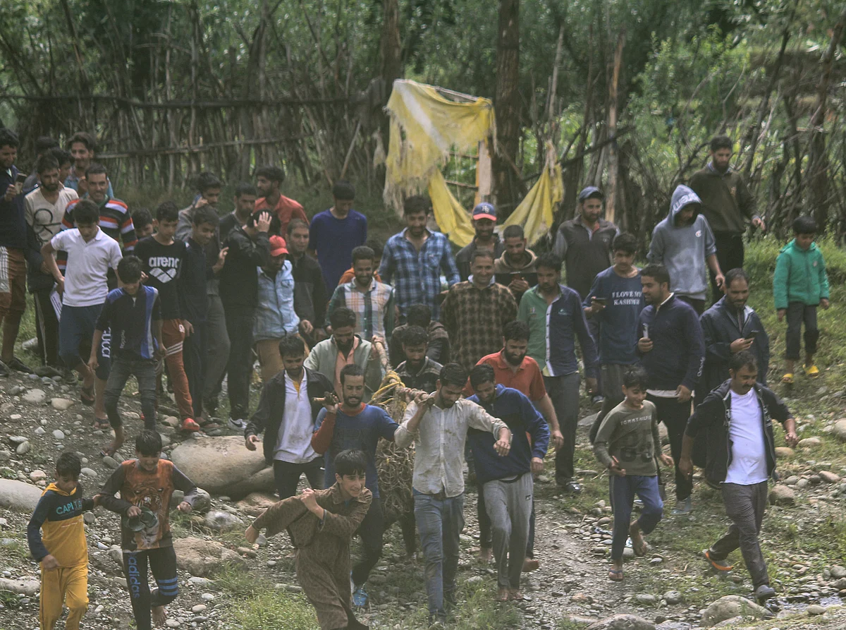 Locals and Wildlife officials carry the tranquilised black bear after it strayed along with its two cubs into northern Kashmir's Baramulla District on July 13, 2021.