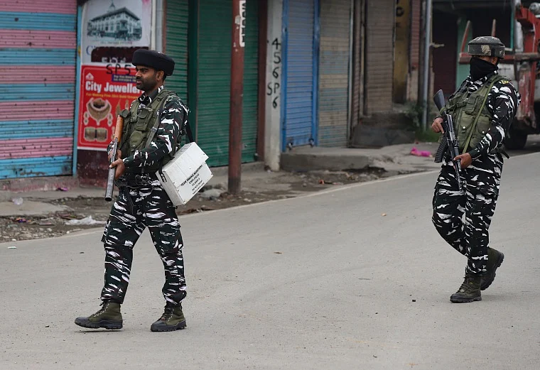 Policemen stand guard on an armored vehicle as they move towards the site of a gunfight in Pulwama town
