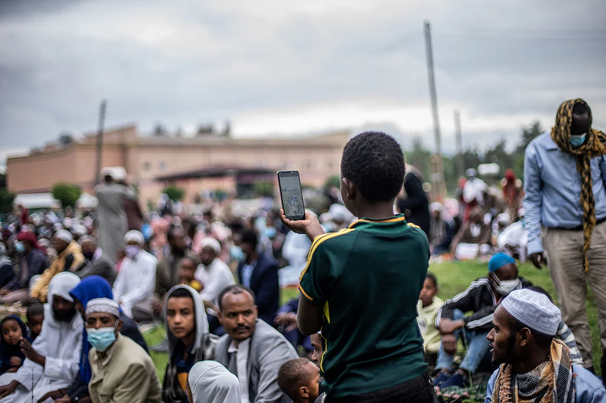 A muslim boy takes pictures during the Eid al-Adha prayers on the first day of the feast celebrated by Muslims worldwide, at the Millennium Square in Hawassa, Ethiopia, on July 20, 2021.
