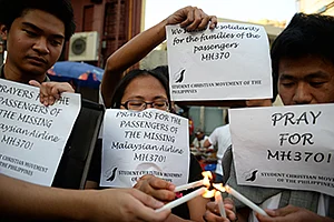 Students light candles as they hold placards in solidarity with families of the<br />passengers of the missing Malaysia plane during a candle light vigil in Manila.