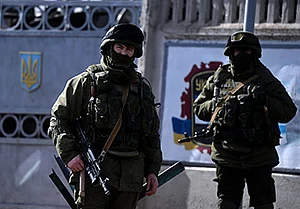 Armed men, believed to be Russian servicemen, stand guard outside an Ukrainian military base in Perevalnoye.