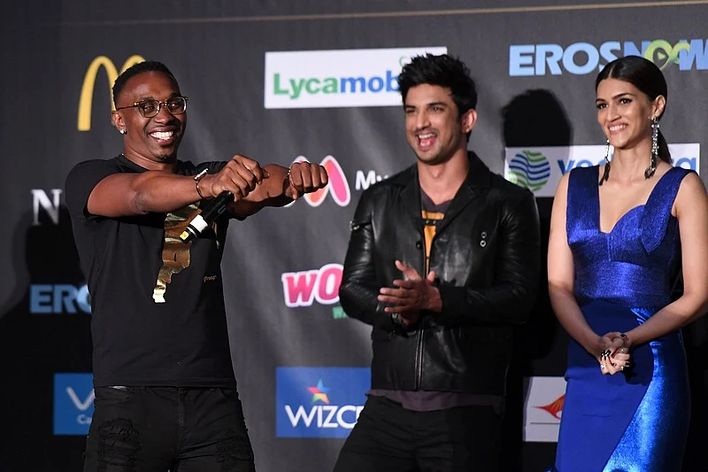 West Indies cricketer Dwayne Bravo (L) is joined by Bollywood actor Sushant Singh Rajput (C) and actress Kriti Sanon as he signs during a press conference ahead of the 18th International Indian Film Academy (IIFA) Festival, in New York City July 13, 2017. / AFP PHOTO / ANGELA WEISS
