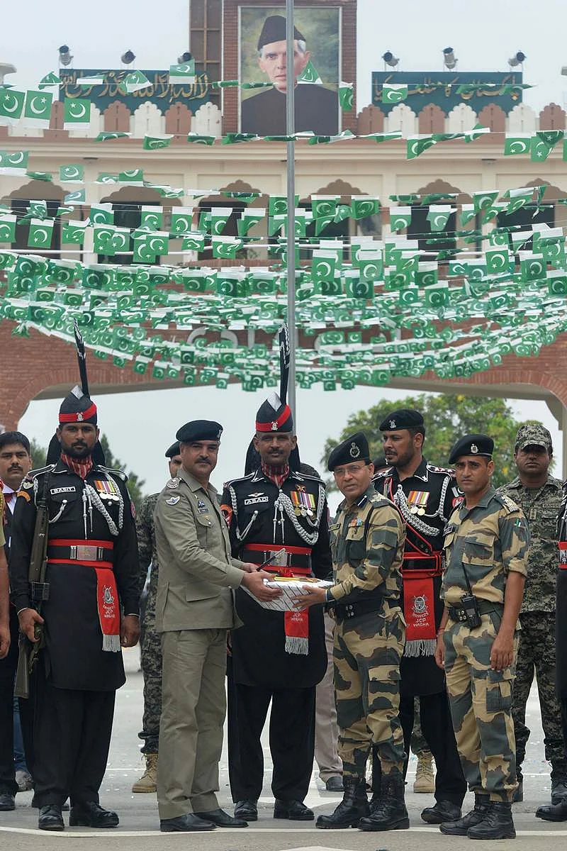 Pakistani Wing Commander Bilal (2L) presents sweets to presents sweets to Indian Border Security Force (BSF) Commandant Sudeep (4R) during a ceremony to celebrate Pakistan’s Independence Day at the India-Pakistan Wagah border post on August 14, 2017. / AFP PHOTO / NARINDER NANU