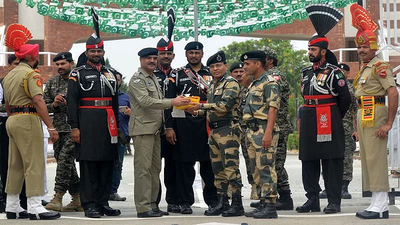 Pakistani Wing Commander Bilal (4L) presents sweets to Indian Border Security Force (BSF) Commandant Sudeep (4R) during a ceremony to celebrate Pakistan’s Independence Day at the India-Pakistan Wagah border post on August 14, 2017. / AFP PHOTO / NARINDER NANU