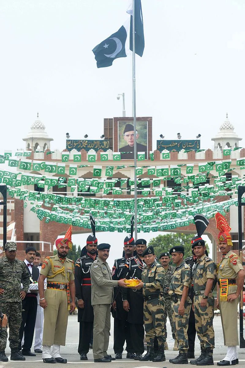 Pakistani Wing Commander Bilal (5L) presents sweets to Indian Border Security Force (BSF) Commandant Sudeep (5R) during a ceremony to celebrate Pakistan’s Independence Day at the India-Pakistan Wagah border post on August 14, 2017. / AFP PHOTO / NARINDER NANU