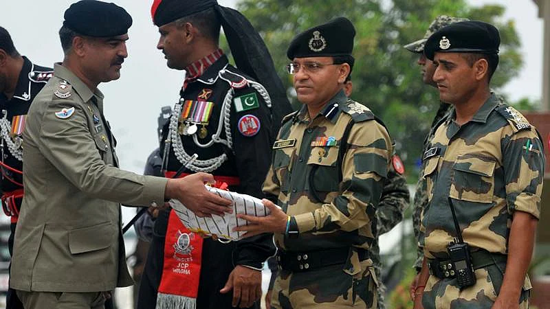 Pakistani Wing Commander Bilal (L)presents sweets to Indian Border Security Force (BSF) Commandant Sudeep (2R) during a ceremony to celebrate Pakistan’s Independence Day at the India-Pakistan Wagah border post on August 14, 2017. / AFP PHOTO / NARINDER NANU