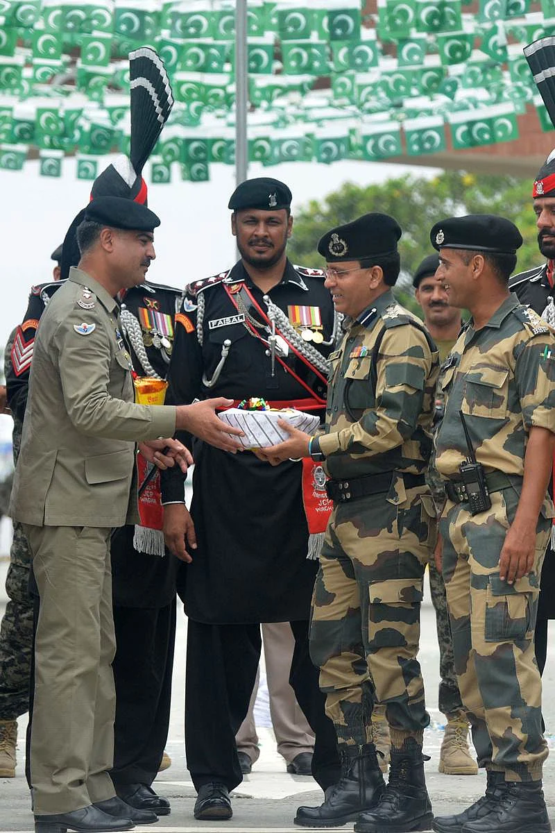 Pakistani Wing Commander Bilal (L) presents sweets to Indian Border Security Force (BSF) Commandant Sudeep (2R) during a ceremony to celebrate Pakistan’s Independence Day at the India-Pakistan Wagah border post on August 14, 2017. / AFP PHOTO / NARINDER NANU