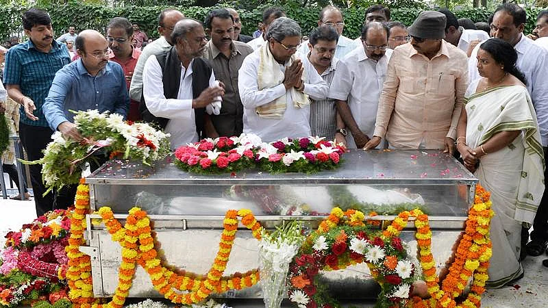 Chief Minister of Karnataka Siddaramaiah (C) along with senior politicians from the state pay their respects next to her body at the Ravindra Kalakshetra cultural centre in Bangalore on September 6, 2017. / AFP PHOTO / MANJUNATH KIRAN