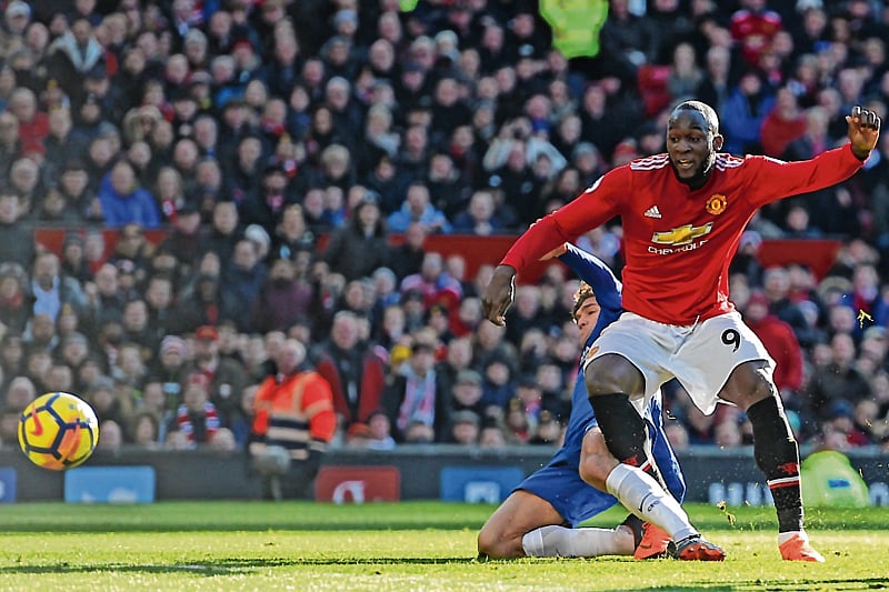 Manchester United's Belgian striker Romelu Lukaku (R) shoots to score their first goal during the English Premier League football match between Manchester United and Chelsea at Old Trafford in Manchester, north west England, on February 25, 2018. / AFP PHOTO / Oli SCARFF / RESTRICTED TO EDITORIAL USE. No use with unauthorized audio, video, data, fixture lists, club/league logos or 'live' services. Online in-match use limited to 75 images, no video emulation. No use in betting, games or single club/league/player publications.  /