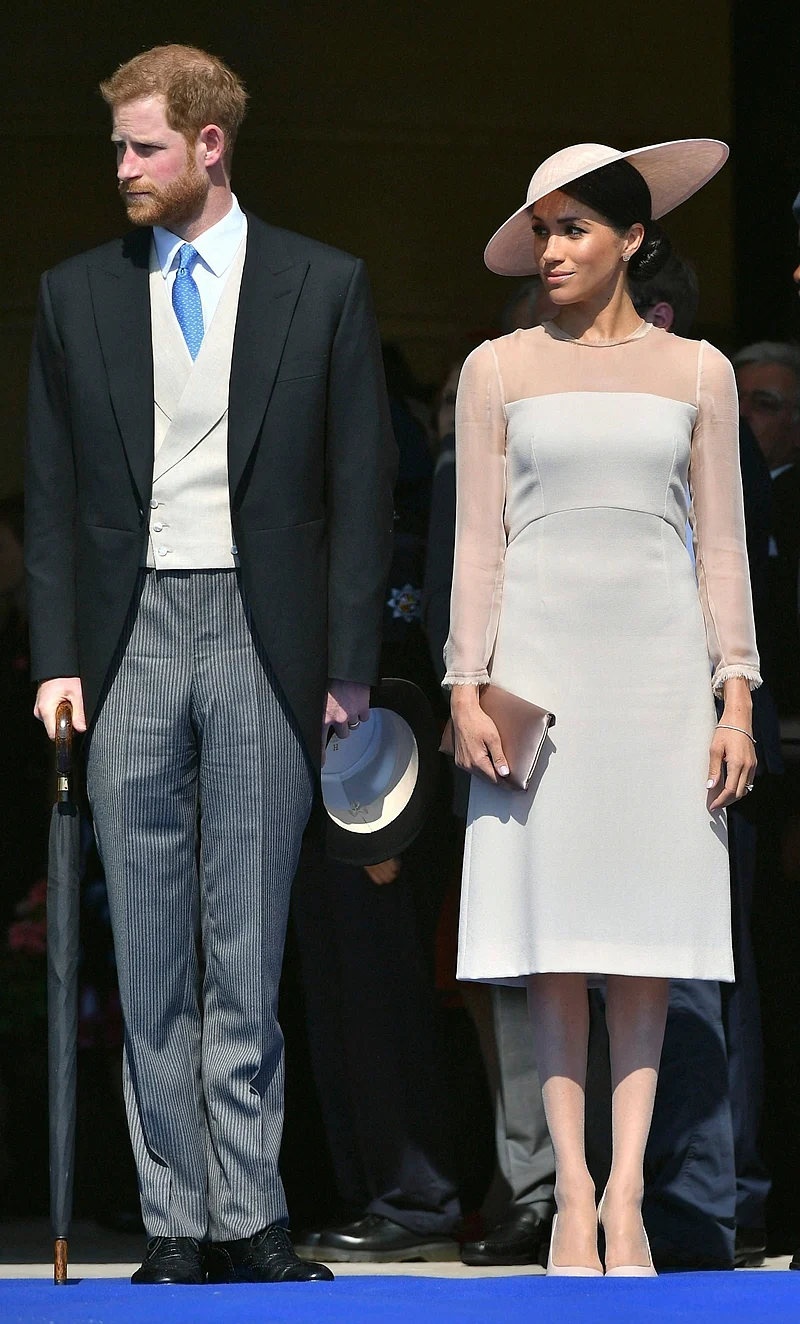 London : Meghan, the Duchess of Sussex stands with her husband, Prince Harry as they attend a garden party at Buckingham Palace in London. AP/PTI