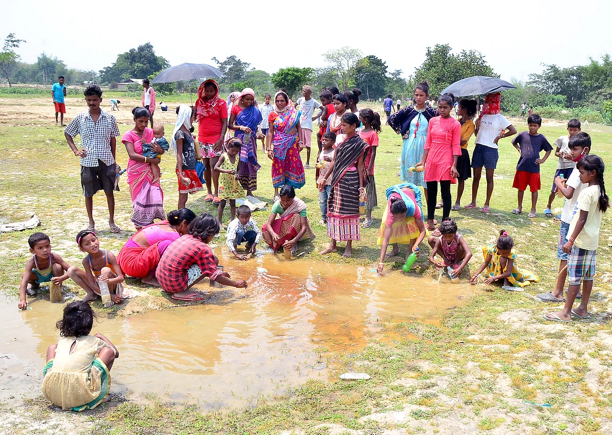 Villagers collect the water seeping out of the cracks on a paddy field caused due to a high-intensity earthquake, at Ghogra Village in Sonitpur district Wednesday. The villagers stored the water out of superstition that it is