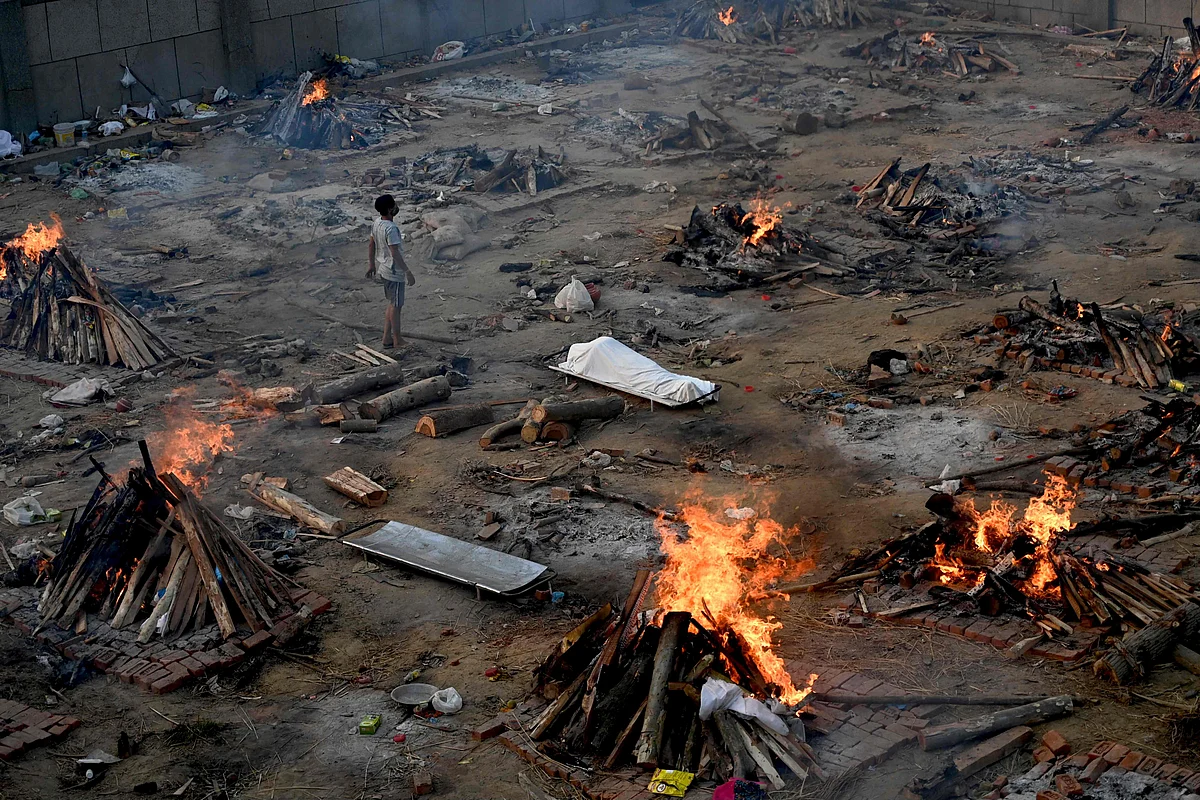 A man stands amid burning pyres of victims who lost their lives due to the Covid-19 coronavirus at a cremation ground in New Delhi on April 26, 2021.
