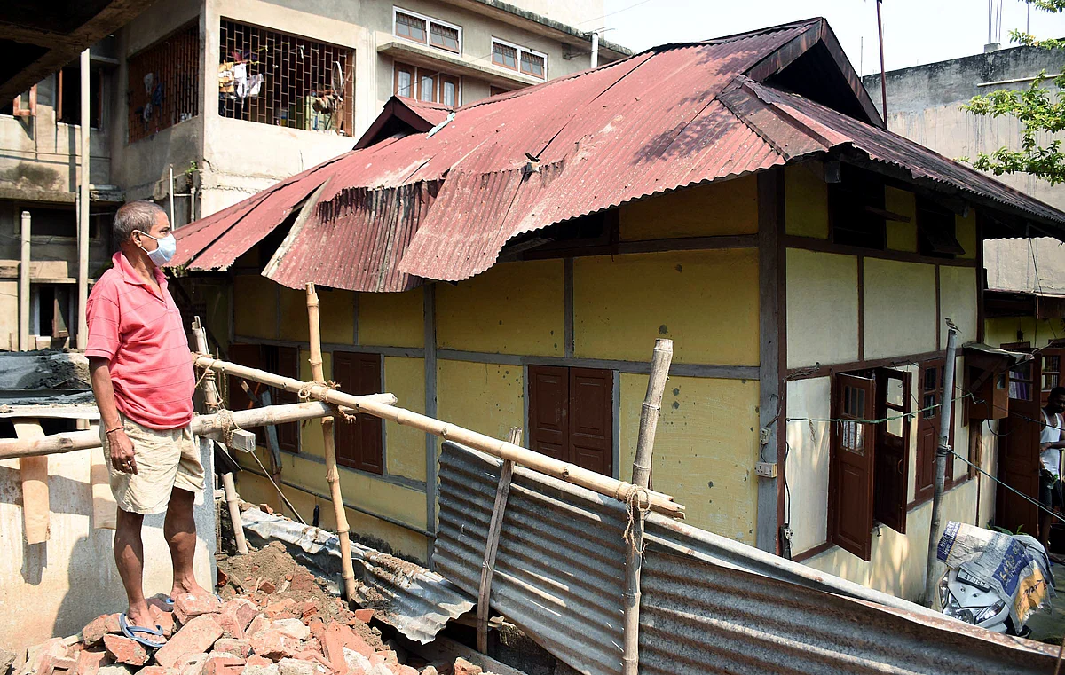 A man seen standing looks on the damaged roof of a house after the earthquake, at Ganeshguri in Guwahati on Wednesday.