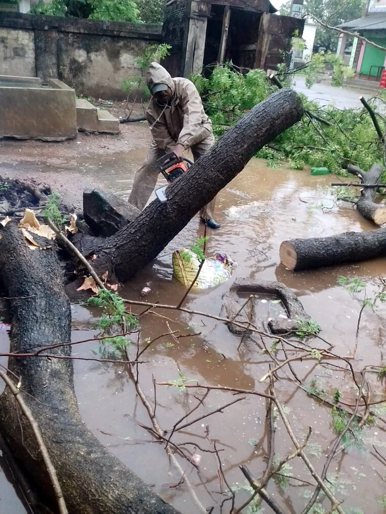 Firefighters personnel clear a fallen tree from a road as they carry out restoration works in the aftermath of Cyclone Yaas