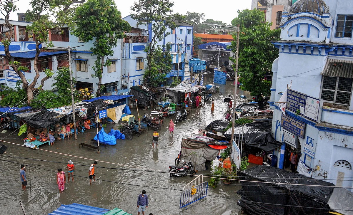Pedestrians wade through a flooded road during landfall of cyclone Yaas, in Kolkata, Wednesday, May 26, 2021.